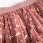 Detalje af tylstof på nederdel til børn med små gyldne prikker og flæser på rosa nederdel