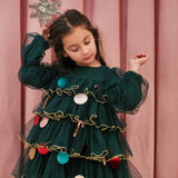 Pige iført mørkegrøn julekjole i tyl med guldkanter og juledetaljer til børn