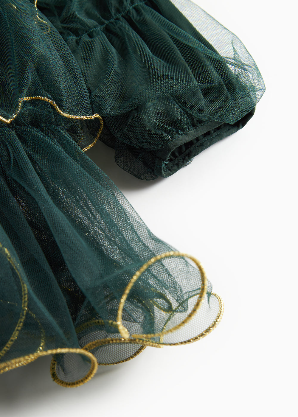 Nærbillede af mørkegrøn julekjole for børn i tyl med guldkanter og flæser