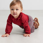 Baby i rød ribbet body med flæsekrave og strikkede bukser