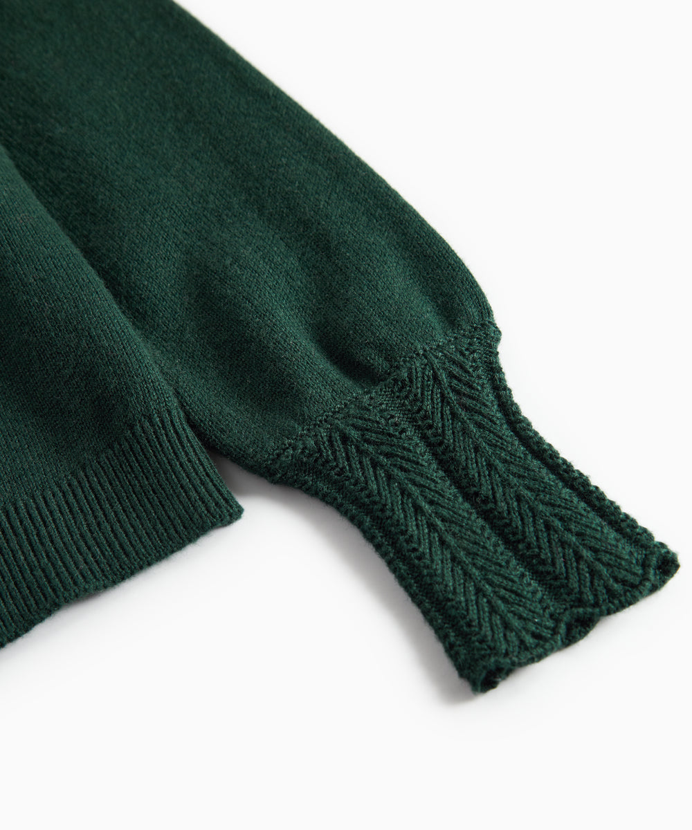 Ärme på mørkegrøn strikket cardigan med hulmønster og ribkanter til baby