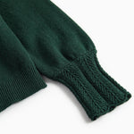 Ärme på mørkegrøn strikket cardigan med hulmønster og ribkanter til baby