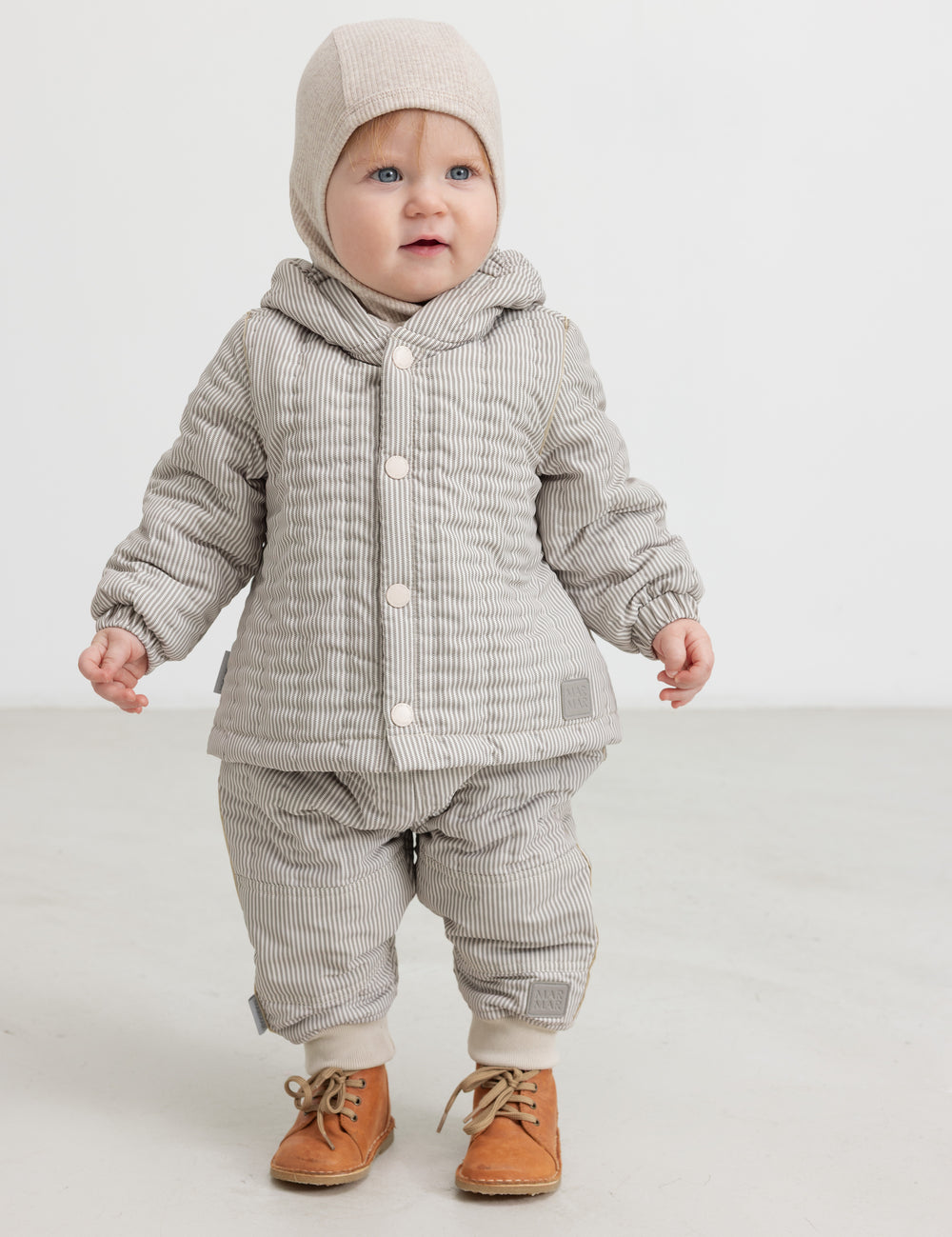 Baby wearing beige thermal pants, matching jacket and hat