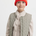 Child wearing a beige fleece jacket and a red knitted hat.