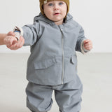 Baby wearing a brown knitted cap and dressed indoors.