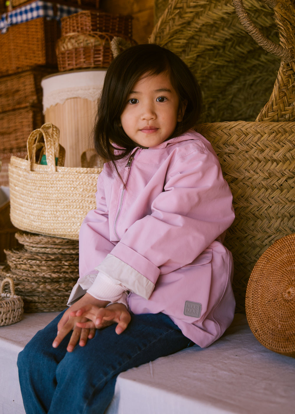 Child wearing a bright red jacket sitting on a bench.