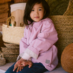 Child wearing a bright red jacket sitting on a bench.