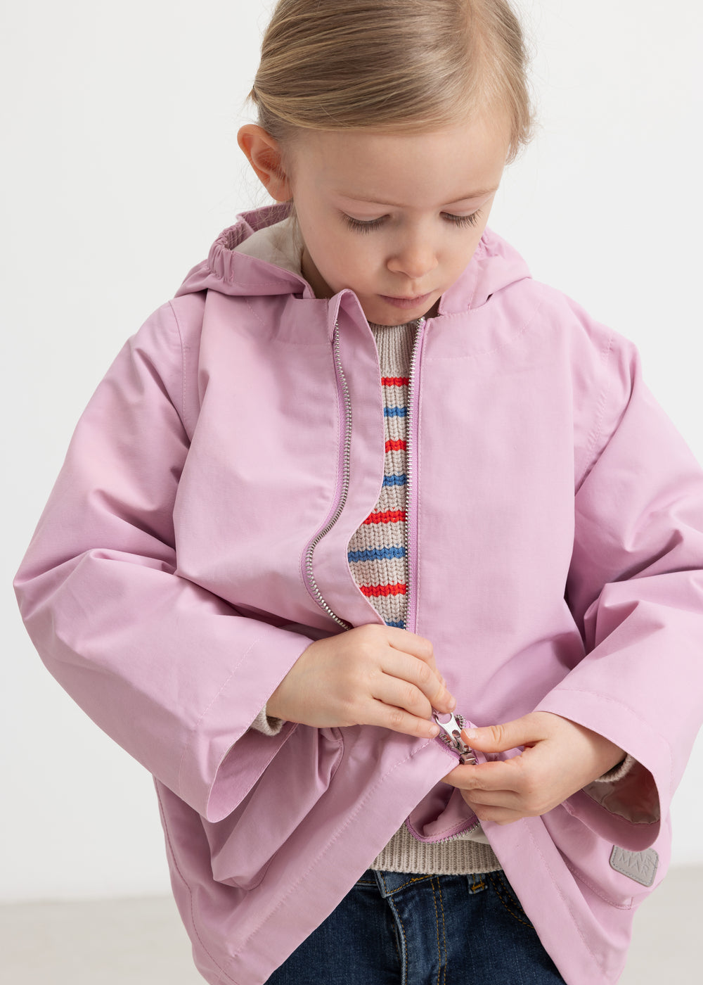 Child wearing a striped sweater with a bright red jacket.