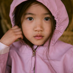 Children in a red safety jacket with a hat close to the face.