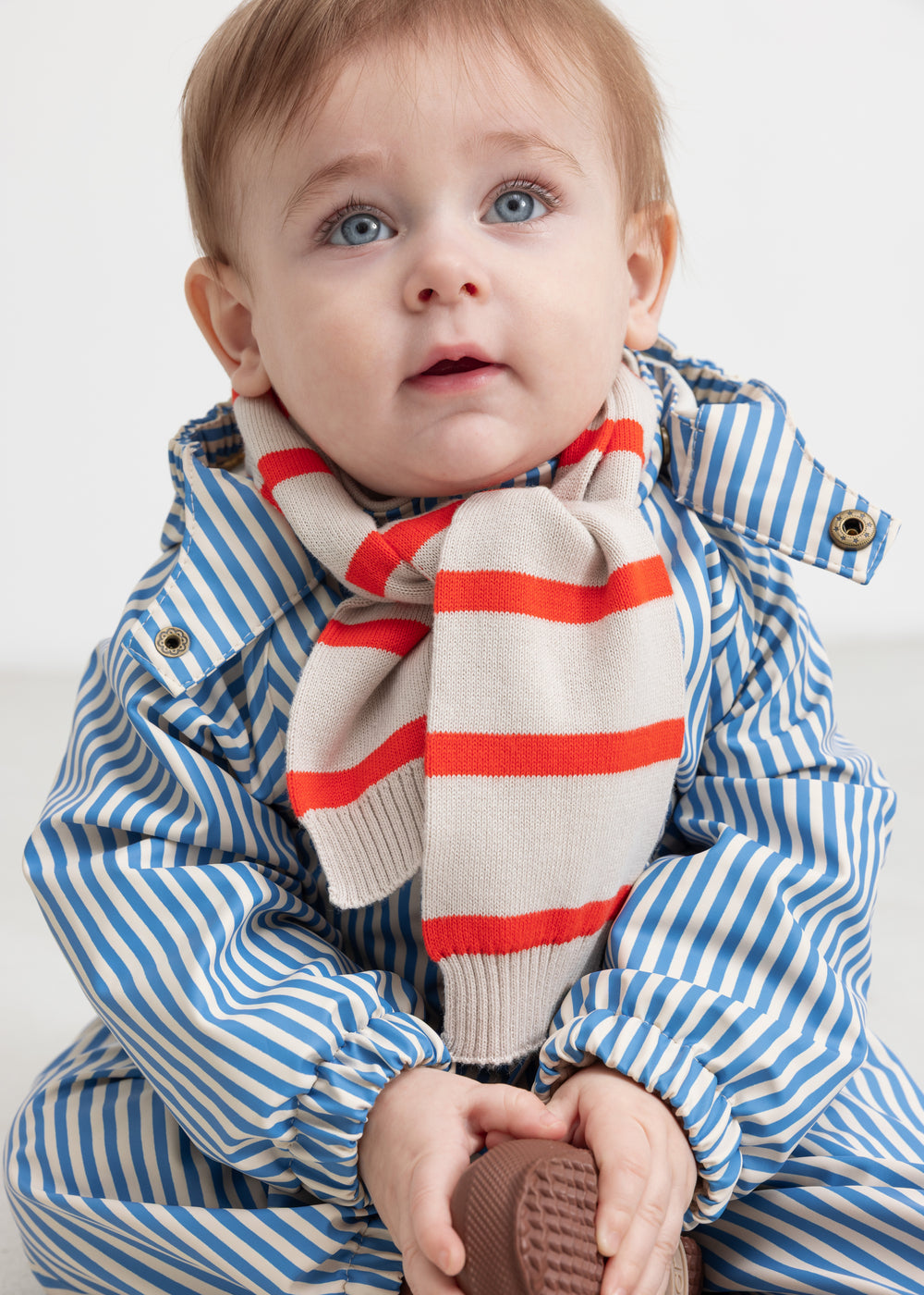 Baby wearing a blue striped raincoat and striped neckerchief.