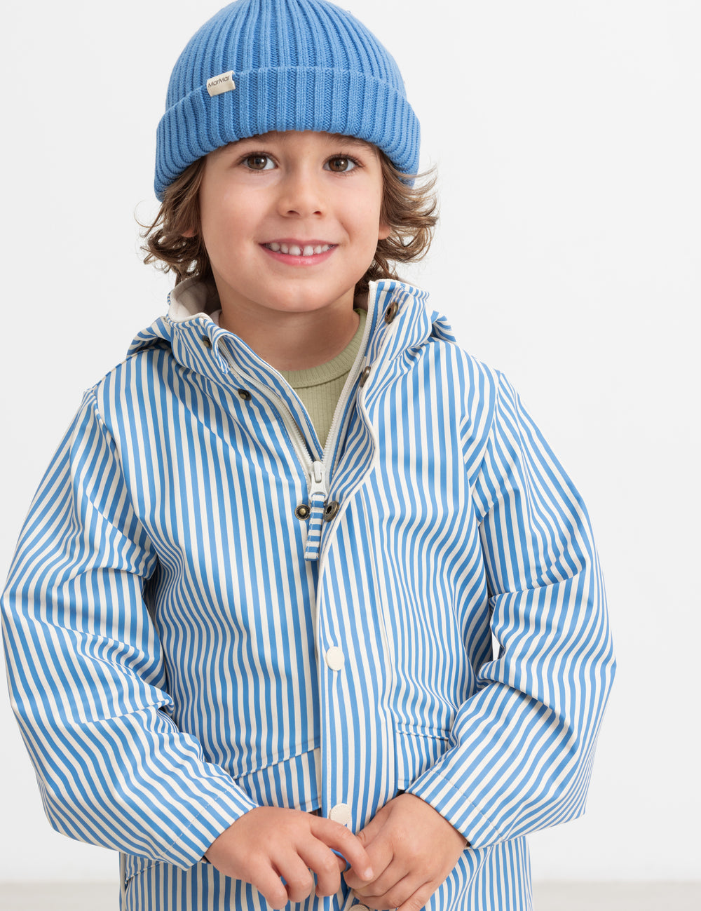 A child wearing a blue knitted hat and striped raincoat.