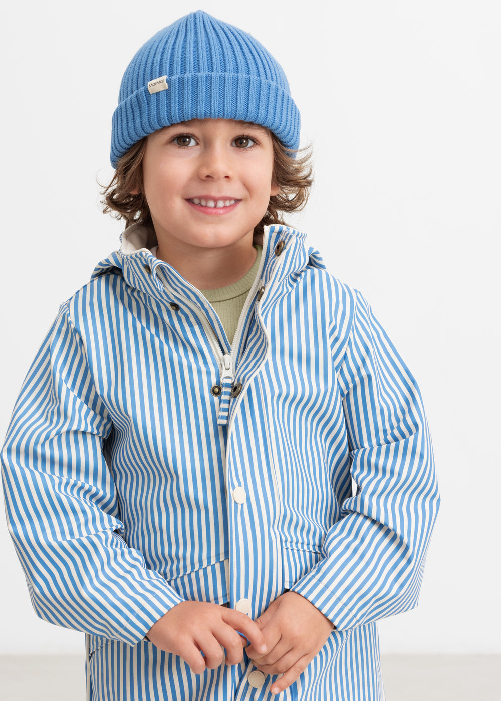 A child wearing a blue knitted hat and striped raincoat.