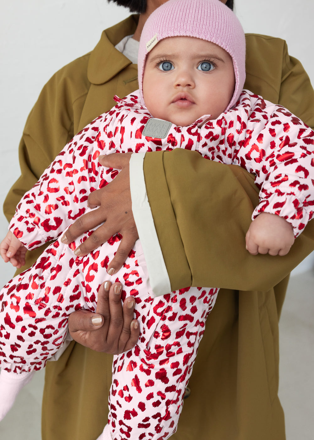 Baby wearing a yellow thermal onesie with leopard print and pink hue.