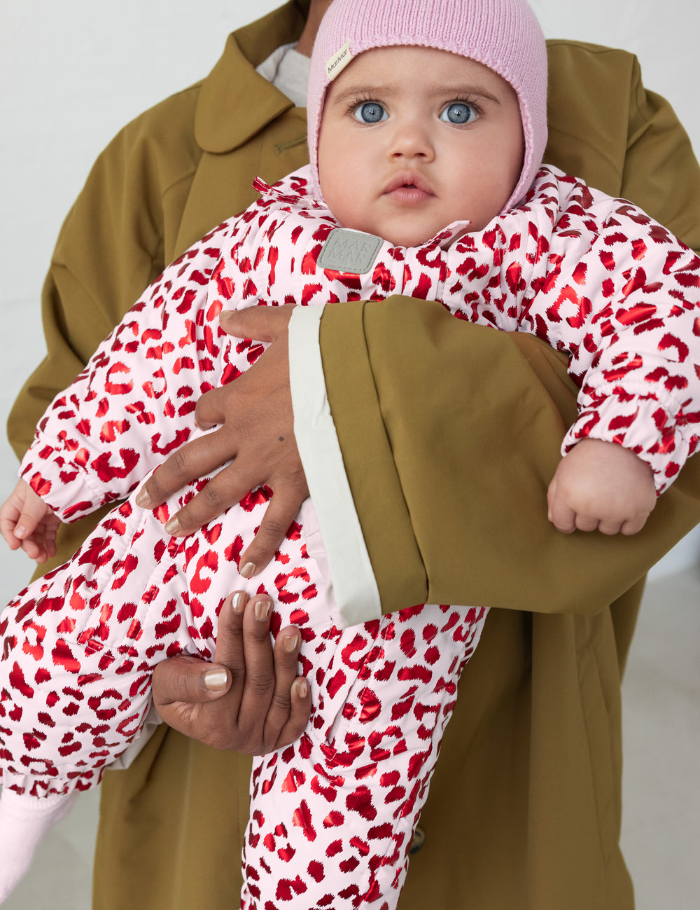 Baby wearing a leopard print onesie and a ribbed hat.