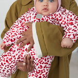 Baby wearing a leopard print onesie and a ribbed hat.