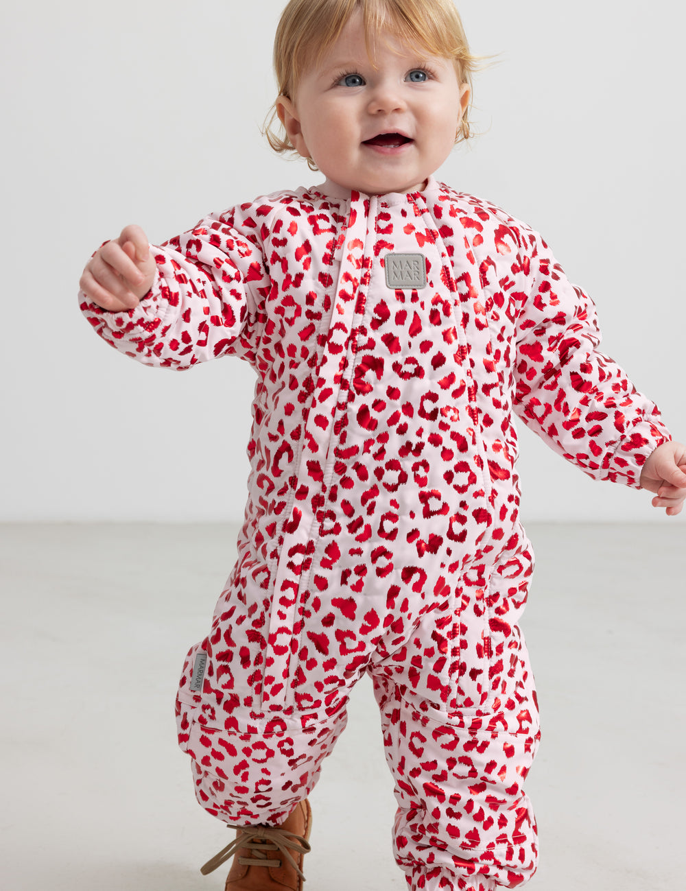 Baby wearing a bright red thermal onesie with leopard print.