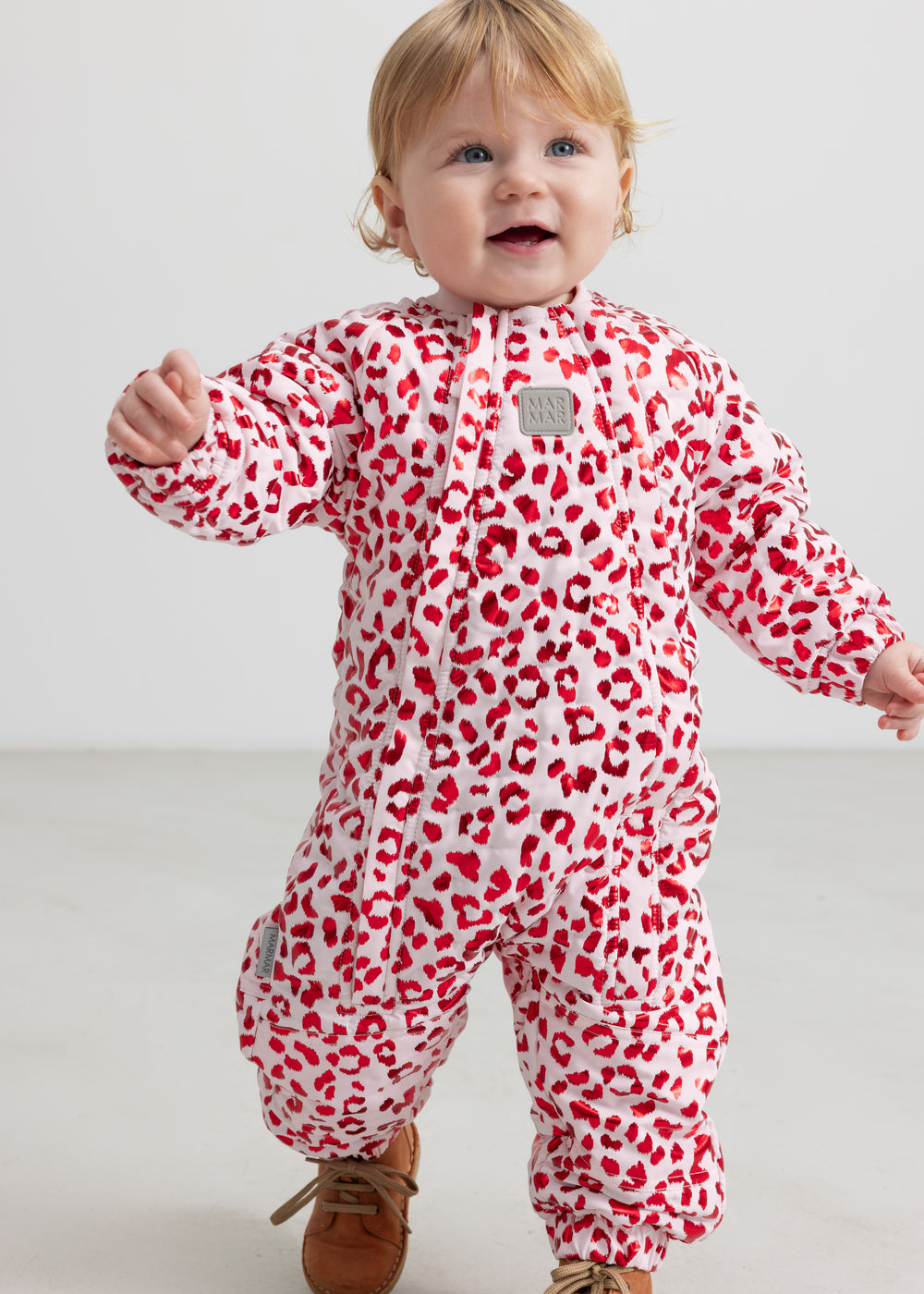 Baby wearing a bright red thermal onesie with leopard print.
