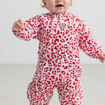 Baby wearing a bright red thermal onesie with leopard print.