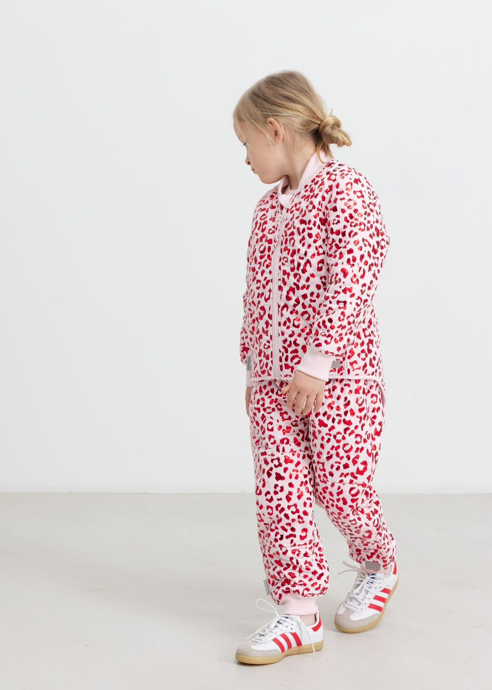 Child wearing a fluorescent red thermal jacket and leopard print pants.