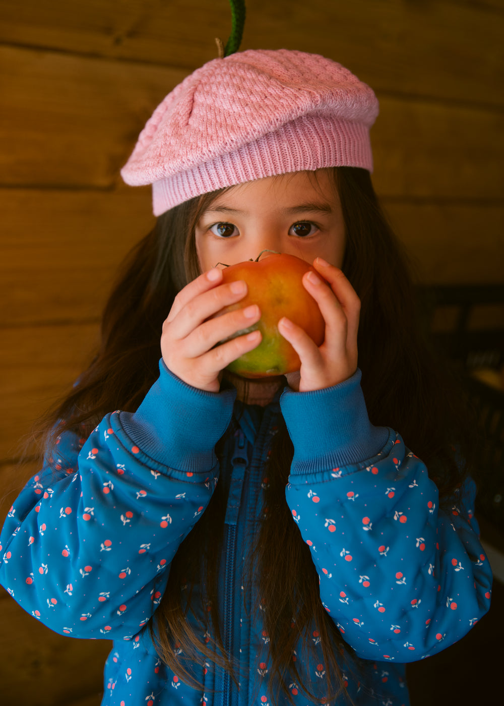 Child wearing a bright red knitted hat and a blue jacket.