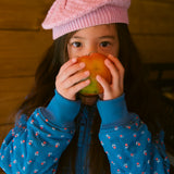 Child wearing a bright red knitted hat and a blue jacket.