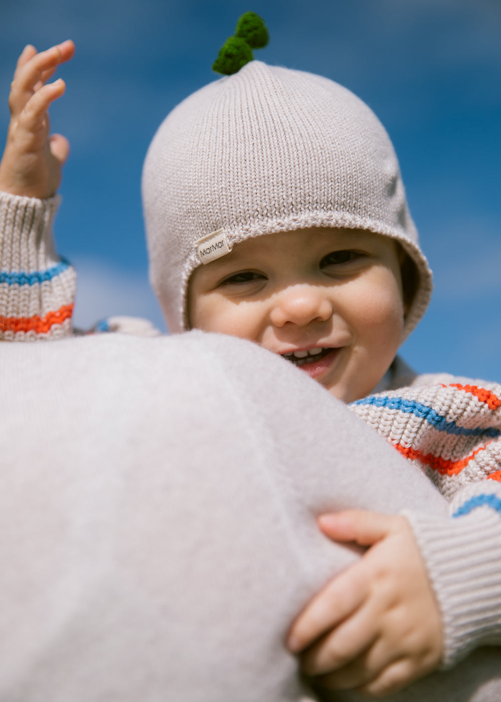 Baby wearing a knitted hat and a striped shirt.