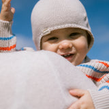 Baby wearing a knitted hat and a striped shirt.