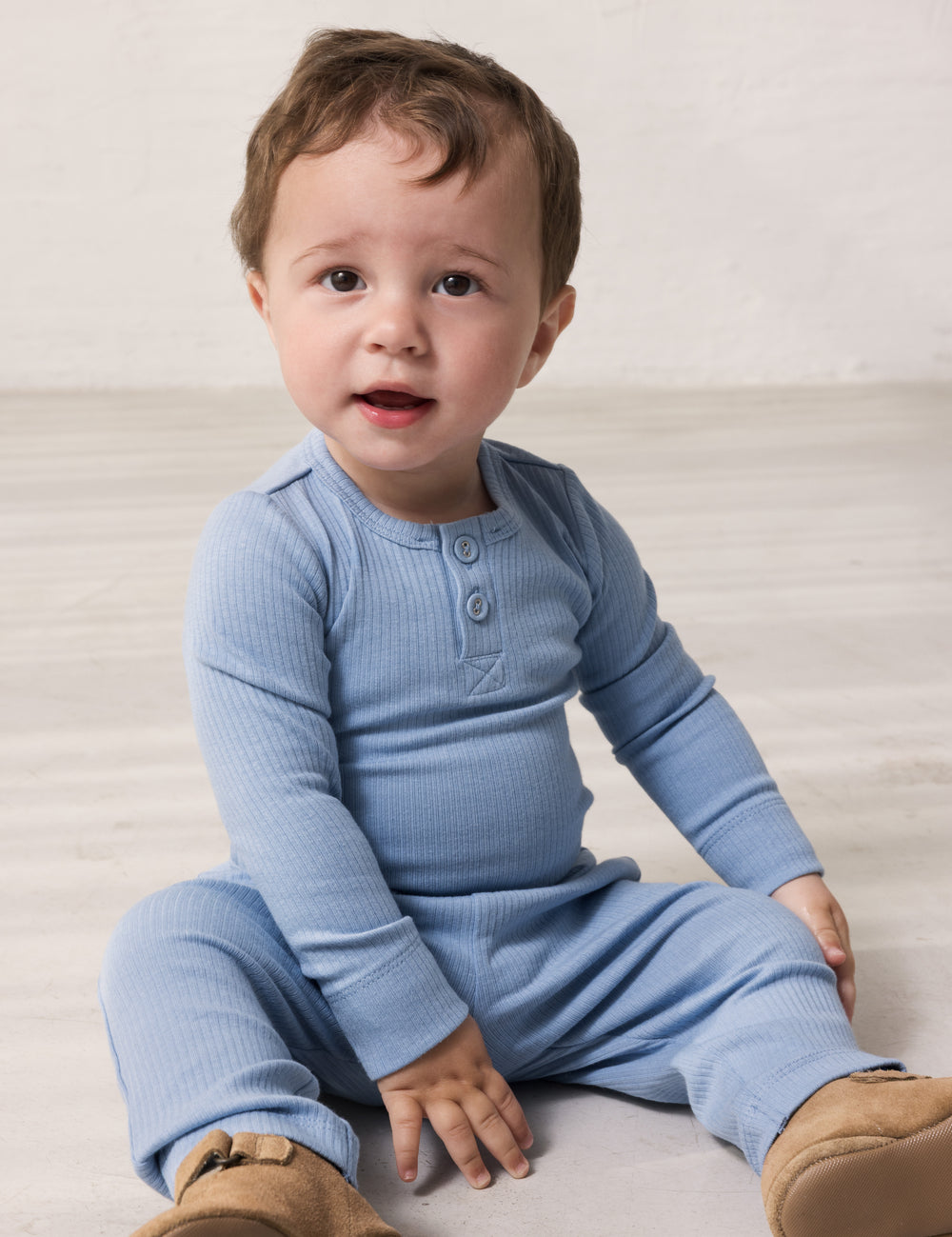 Baby wearing light blue long-sleeved bodystocking with g-string closure and matching pants.