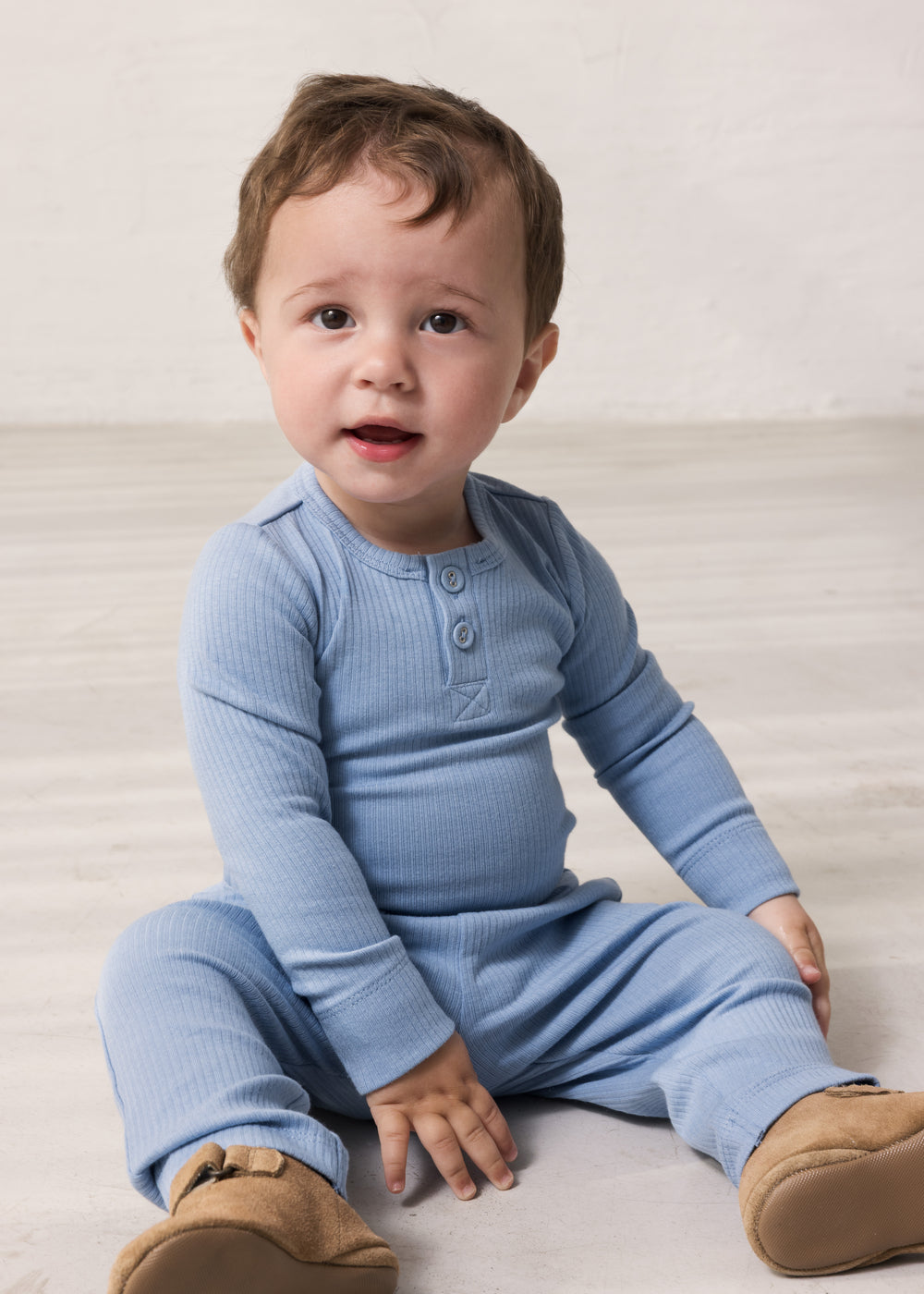 Baby wearing light blue long-sleeved bodystocking with g-string closure and matching pants.