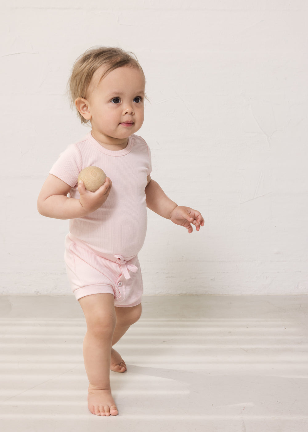 Baby wearing red short-sleeved baby bodystocking and bloomers