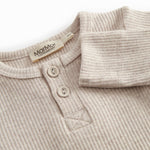 Beige baby pants with elastic and a decorative band at the waist.