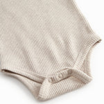 Beige baby pants with elastic and a decorative band at the waist.