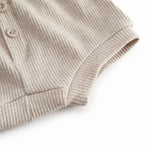 Beige baby bloomers with a drawstring and a decorative band at the waist.