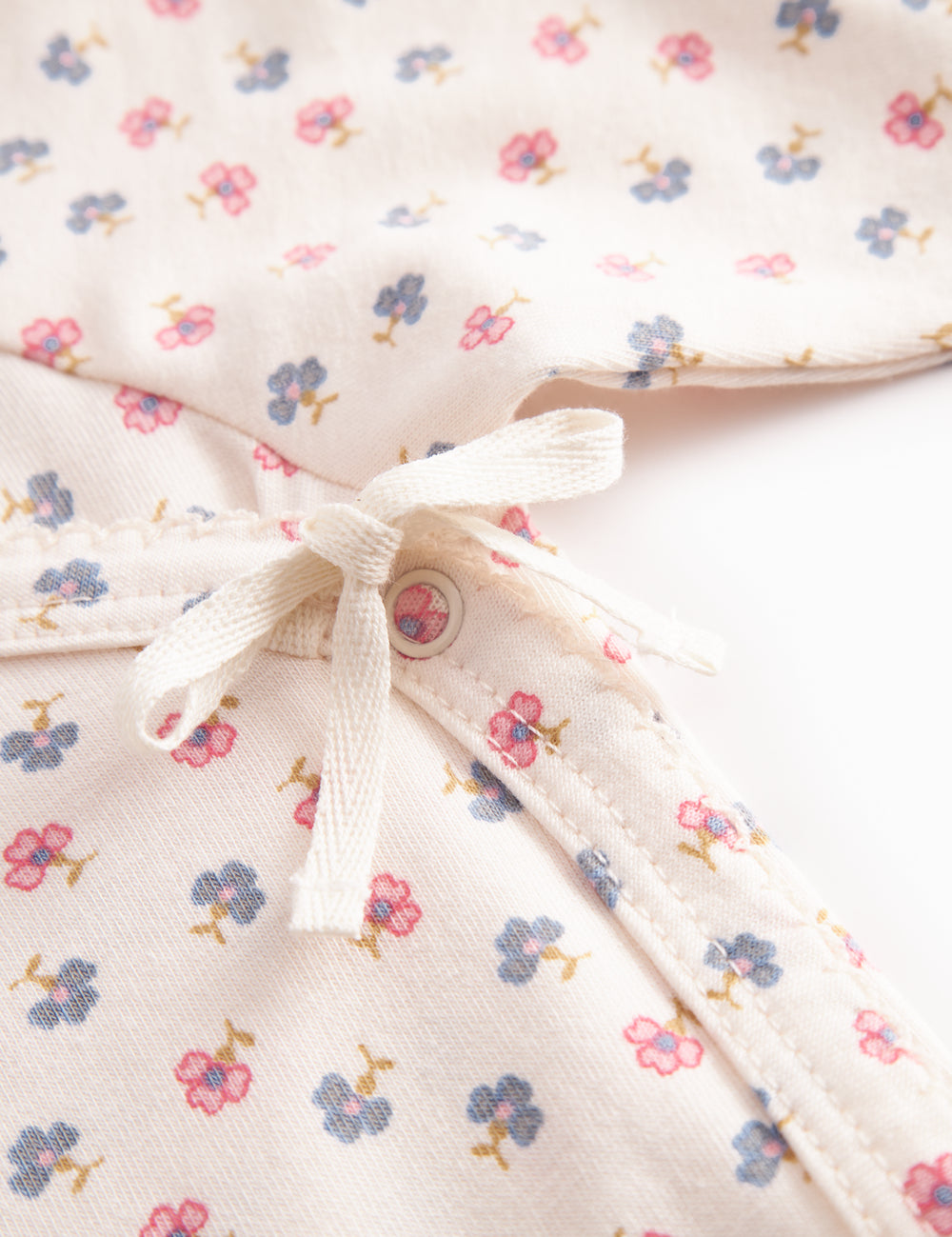 Langærmet bodystocking for a newborn baby with snap closure and flowers.