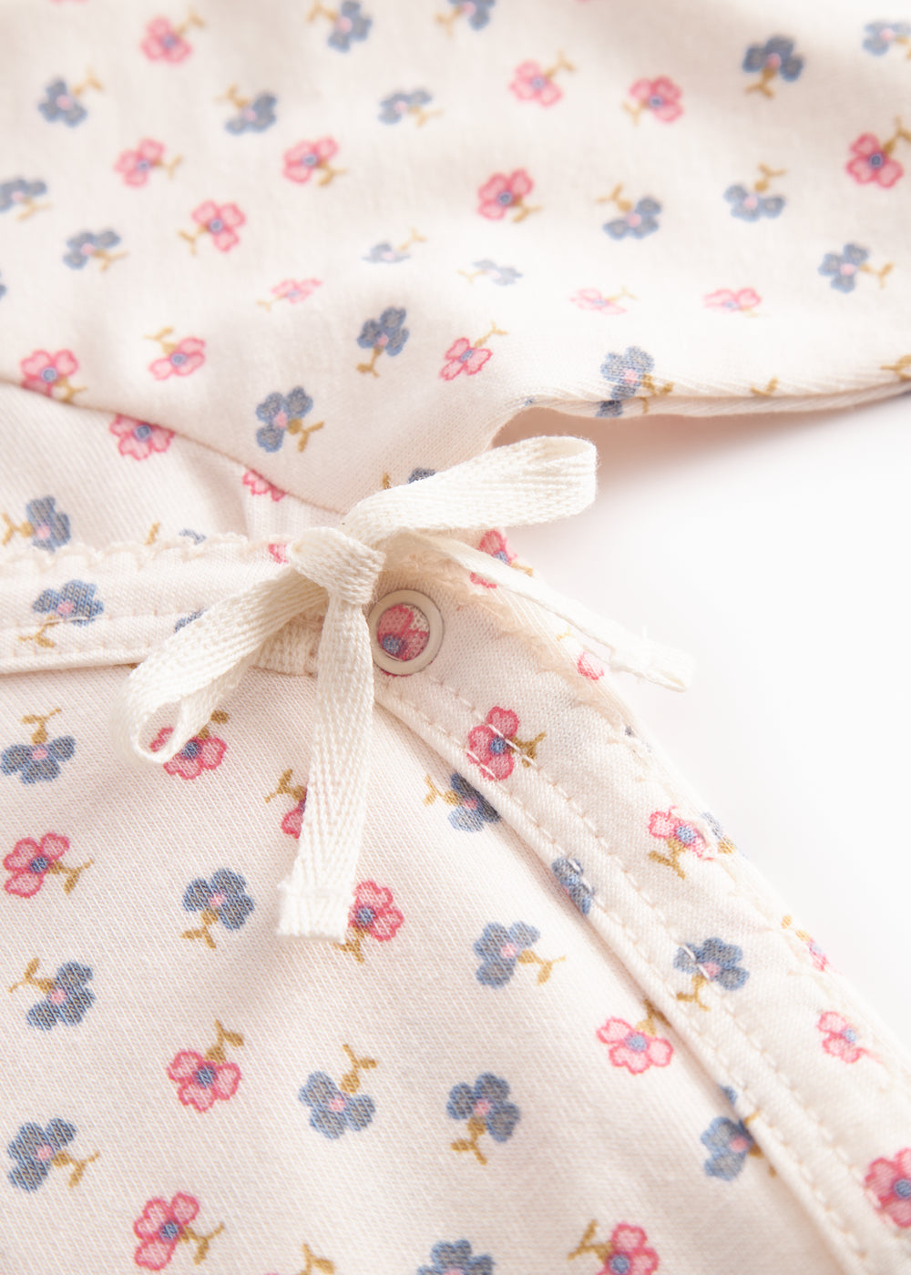 Langærmet bodystocking for a newborn baby with snap closure and flowers.