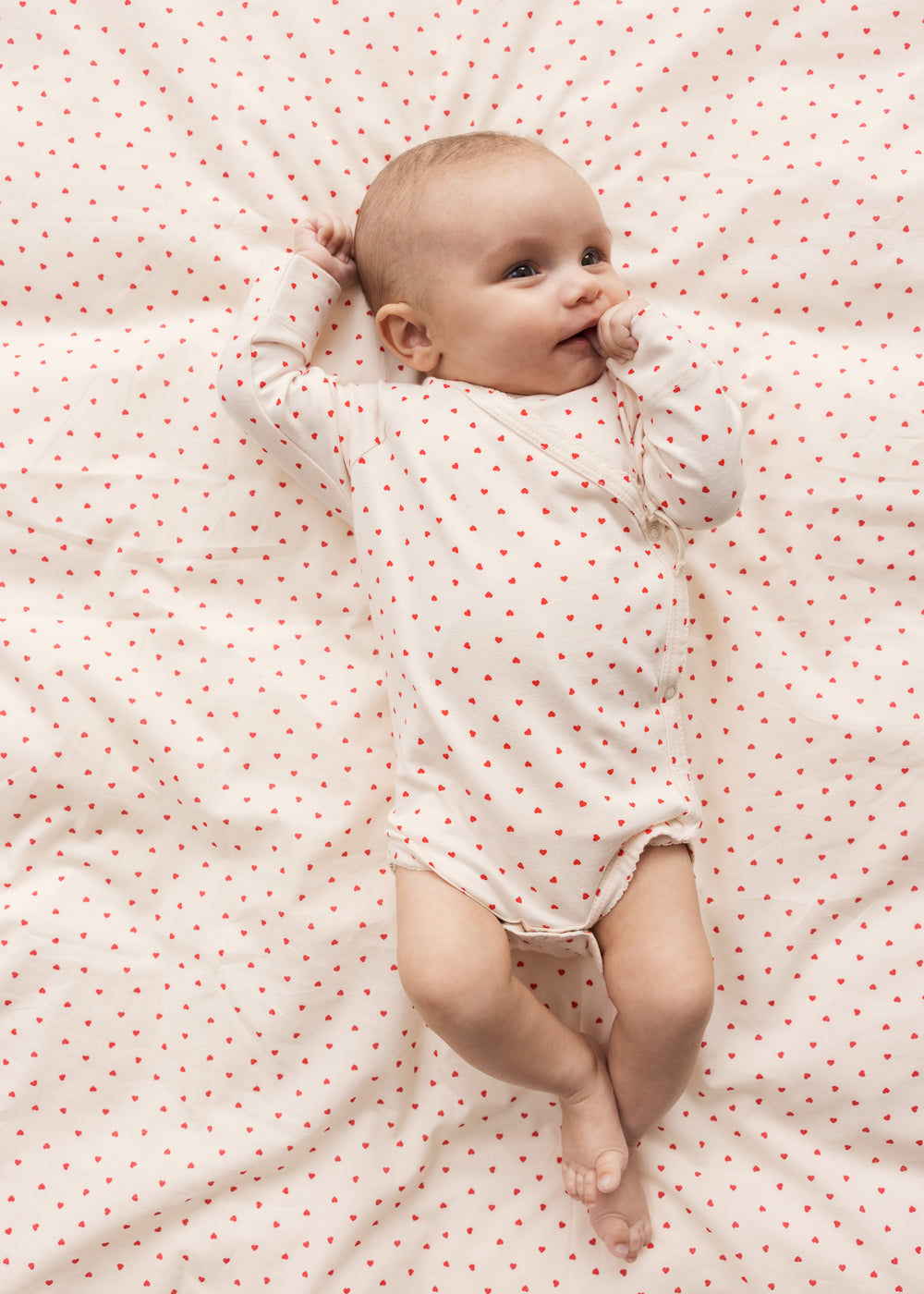 Baby lying on bedding with small hearts
