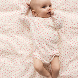 Baby lying on bedding with small hearts
