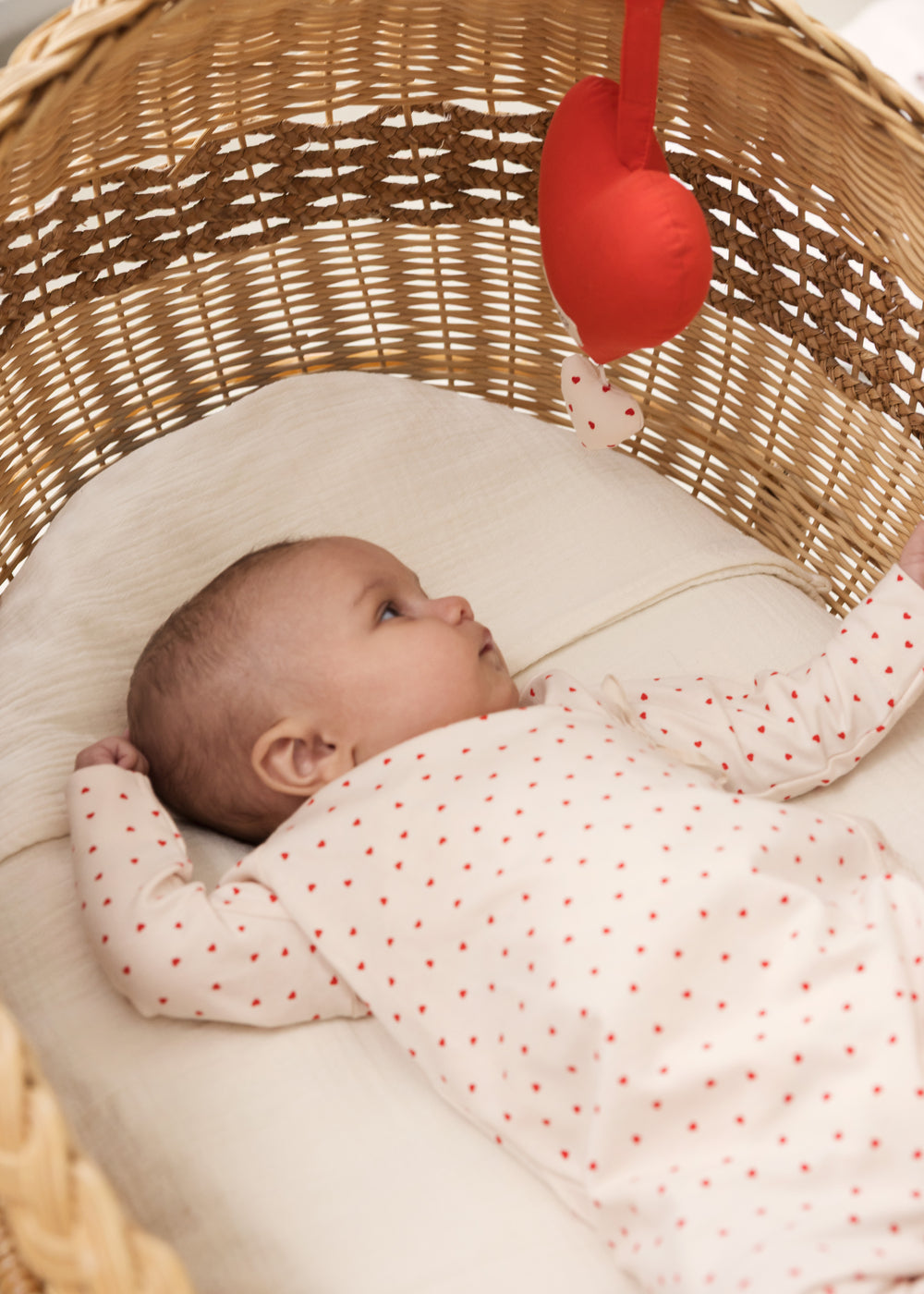 Baby lying in the cart with a red music blanket over them.