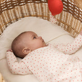Baby lying in the cart with a sparkly onesie and small hearts, with a red music note over it.
