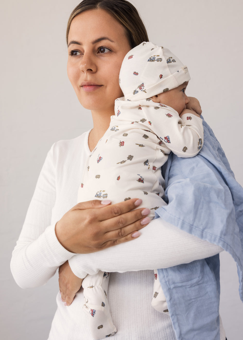 Baby held by a woman with a fabric blanket over her shoulder.