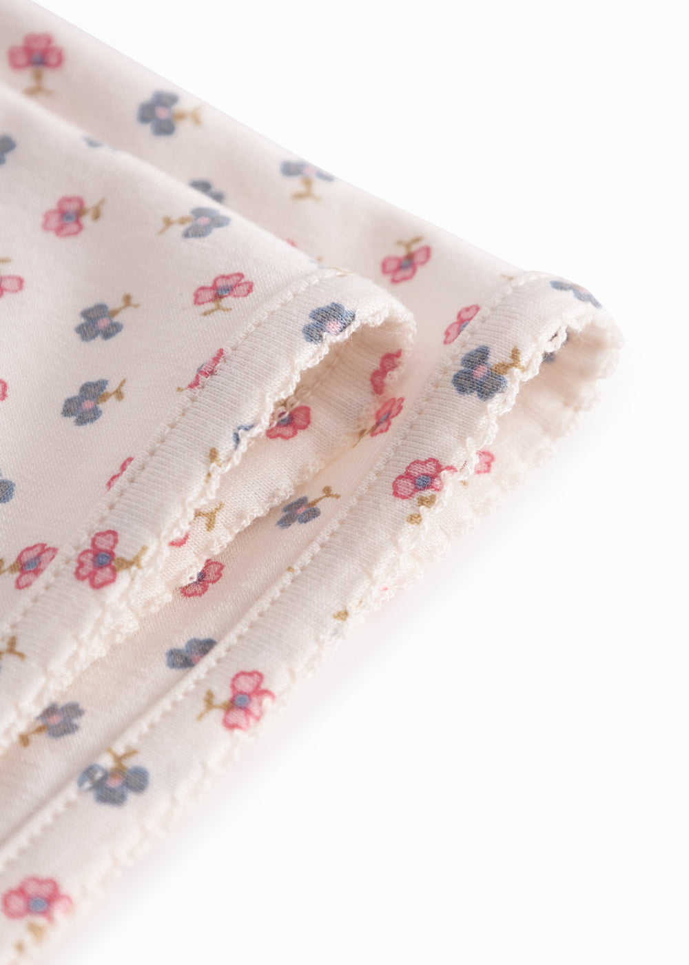 Baby blanket with rounded corners, picot edges, and floral print.