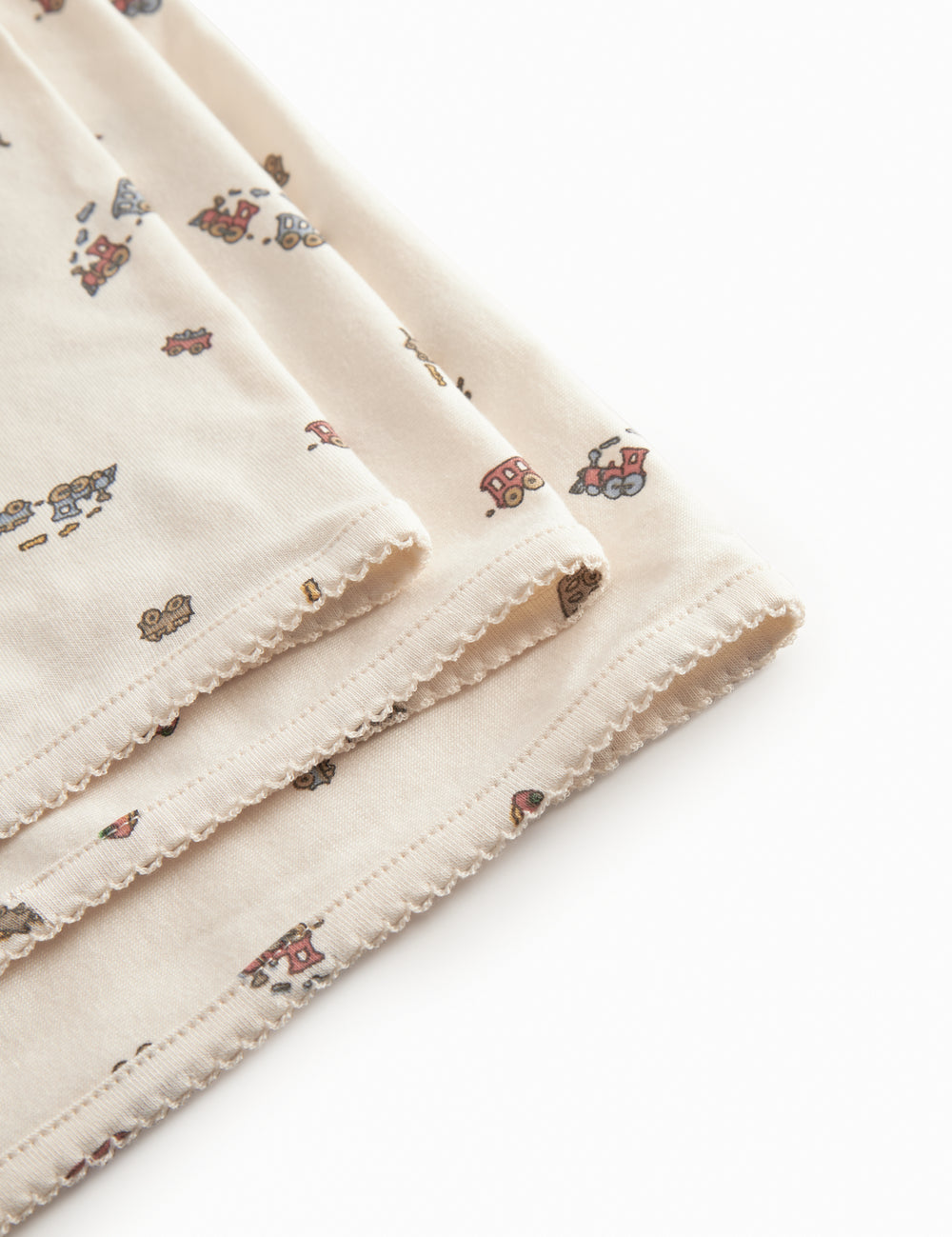 Baby blanket with rounded corners, picot edges, and train print.