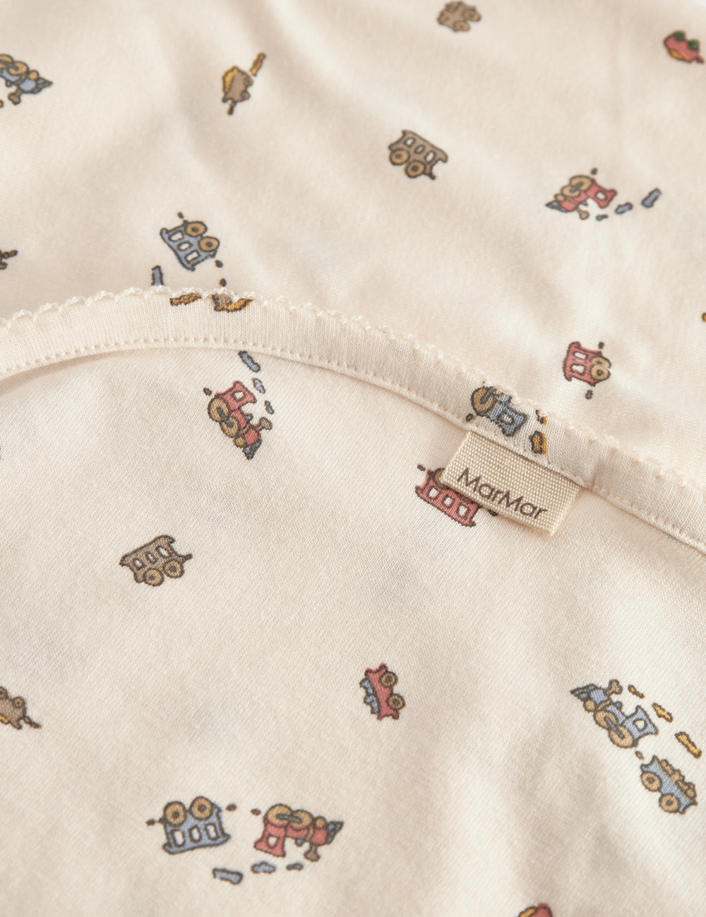 Baby blanket with rounded corners, picot edges, and train print.