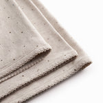 Beige baby blanket with rounded corners, picot edges, and a fine print.