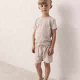 Boy wearing a beige short-sleeved t-shirt and shorts