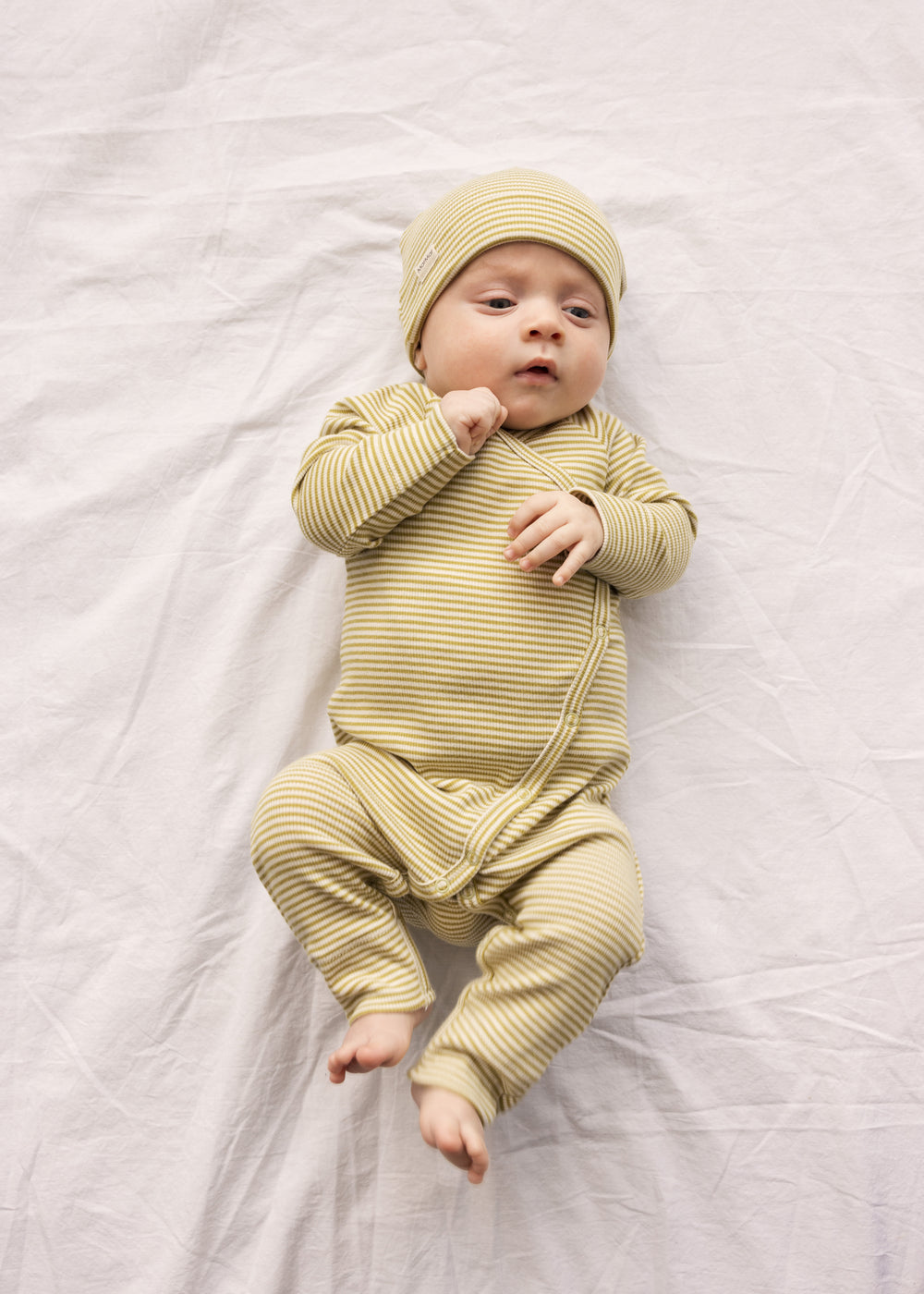 Baby wearing a green-striped onesie and matching hat.