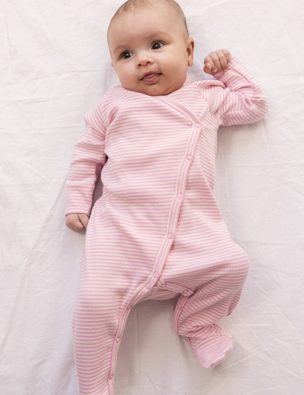 Baby wearing a long-sleeved onesie with feet and bright red stripes.