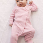 Baby wearing a long-sleeved onesie with feet and bright red stripes.