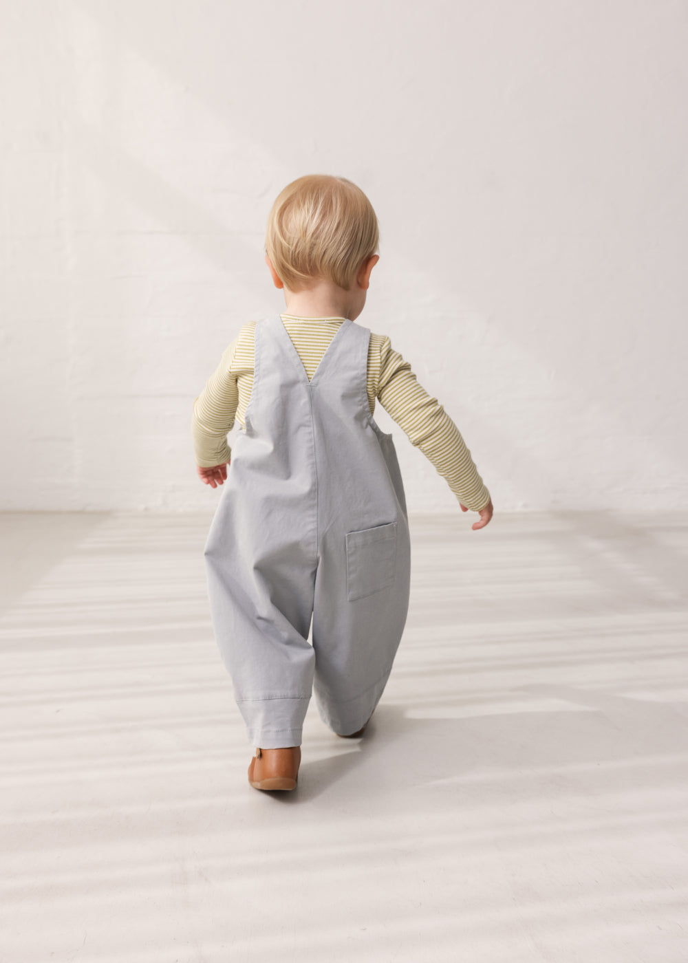 Children wearing green striped bodies under gray overalls.