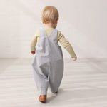 Baby wearing light blue chino shorts and a green body.